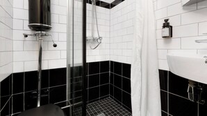 Ein modernes Badezimmer mit schwarz-weiß gefliestem Design, einer Duschkabine aus Glas und einem weißen Waschbecken.