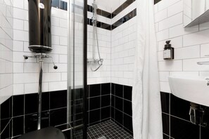 Ein modernes Badezimmer mit schwarz-weiß gefliestem Design, einer Duschkabine aus Glas und einem weißen Waschbecken.
