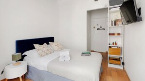 Ein Schlafzimmer mit Bett, Nachttisch, Wand-Fernseher und Kleiderschrank.