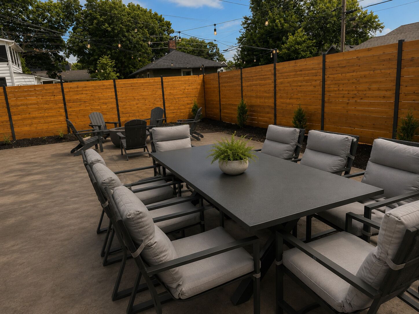 Eine Terrasse im Freien mit einem rechteckigen Tisch und sechs Stühlen, umgeben von einem Holzzaun.