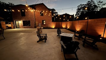 An outdoor patio with brick walls, string lights, and outdoor furniture.