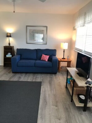A living room with a blue sofa, a framed picture on the wall, a television, and a lamp. - N. Wildwood Cottage 2 1/2 blocks to beach (North Wildwood)