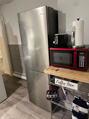 A kitchen with a stainless steel refrigerator, a black coffee maker, a red microwave, and a coffee bar area. - N. Wildwood Cottage 2 1/2 blocks to beach (North Wildwood)