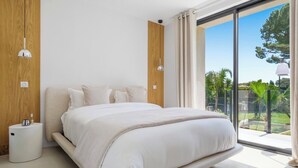 A modern bedroom with a large bed, a bedside table, and a view of the outdoors. - Stunning Villa in Cap d'Antibes for 6 Guests, Ocean View, Air Conditioning (Antibes)