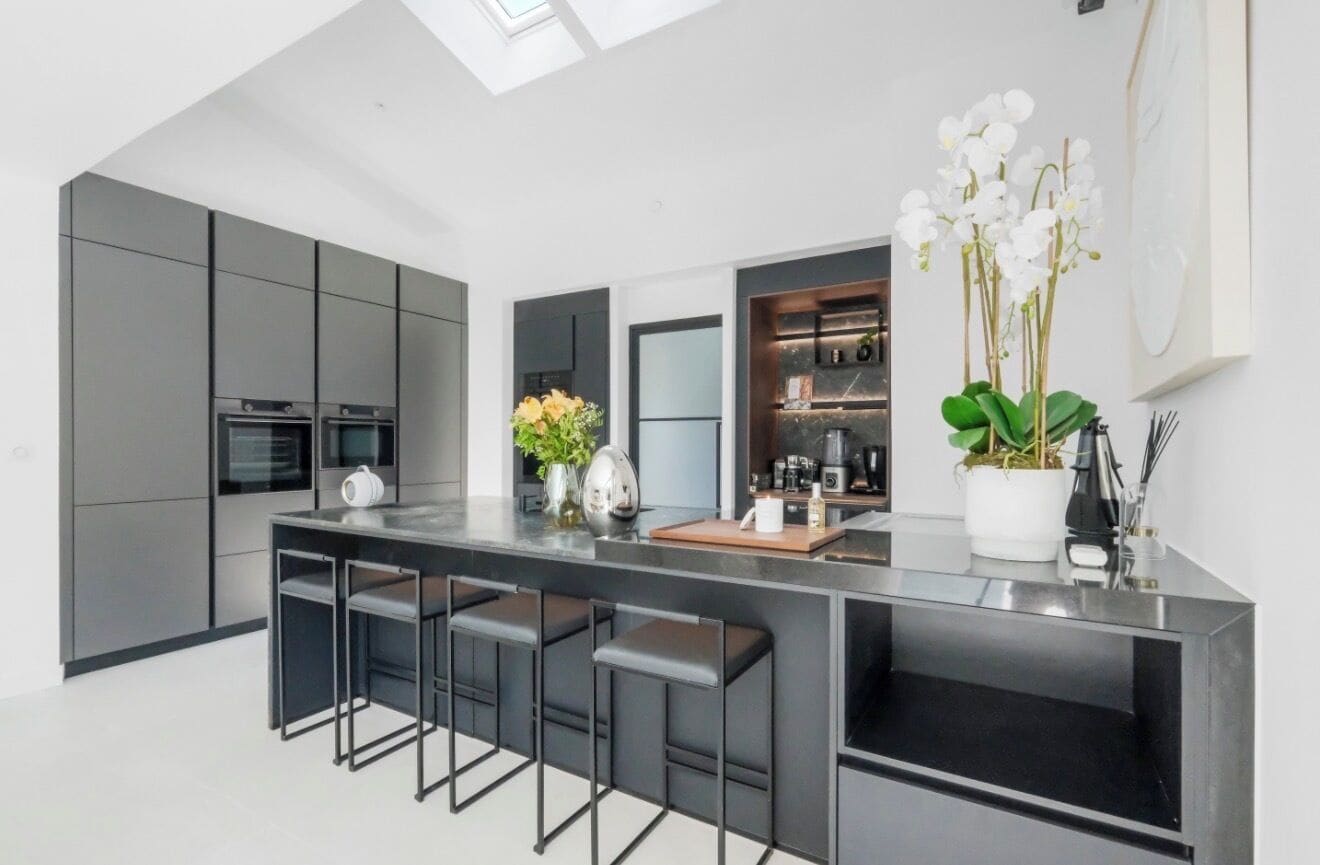 A modern kitchen with a central island, bar stools, and a skylight.