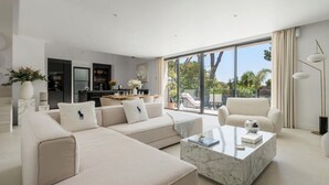 A modern living room with a sectional sofa, a marble coffee table, and a view of the outdoors through large windows. - Stunning Villa in Cap d'Antibes for 6 Guests, Ocean View, Air Conditioning (Antibes)