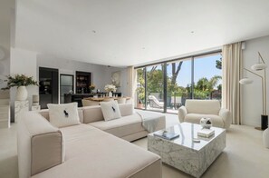 A modern living room with a sectional sofa, a marble coffee table, and a view of the outdoors through large windows. - Stunning Villa in Cap d'Antibes for 6 Guests, Ocean View, Air Conditioning (Antibes)