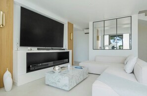 A modern living room with a large flat-screen TV mounted on a white wall, a white sofa, a marble coffee table, and a minimalist decor style. - Stunning Villa in Cap d'Antibes for 6 Guests, Ocean View, Air Conditioning (Antibes)