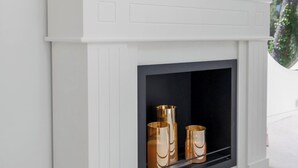 A white fireplace with a black surround, a decorative plate, and two golden vases. - Stunning Villa in Cap d'Antibes for 6 Guests, Ocean View, Air Conditioning (Antibes)
