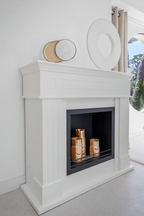 A white fireplace with a black surround, a decorative plate, and two golden vases. - Stunning Villa in Cap d'Antibes for 6 Guests, Ocean View, Air Conditioning (Antibes)