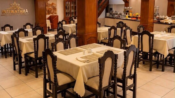 Un restaurante con varias mesas y sillas, arcos de madera y una cocina a la vista.