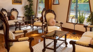 Amplia habitación con candelabro, ventanas grandes y muebles clásicos.