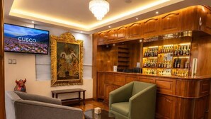 Una zona de bar con armarios de madera y un televisor colgado en la pared.