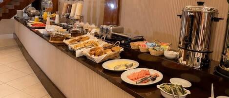 A buffet setup with various food items and beverages, a coffee machine, and a water dispenser.