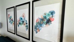 Tre quadri astratti incorniciati appesi a una parete.