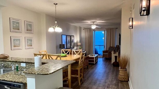 Una cucina moderna con piani di lavoro in granito, lavastoviglie e zona pranzo con tavolo e sedie in legno.