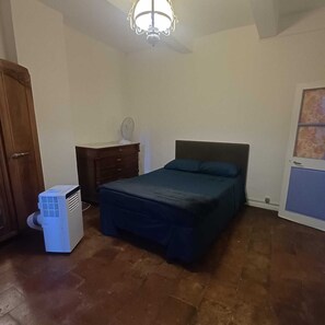 A bedroom with a bed, a dresser, a heater, and a ceiling light fixture.