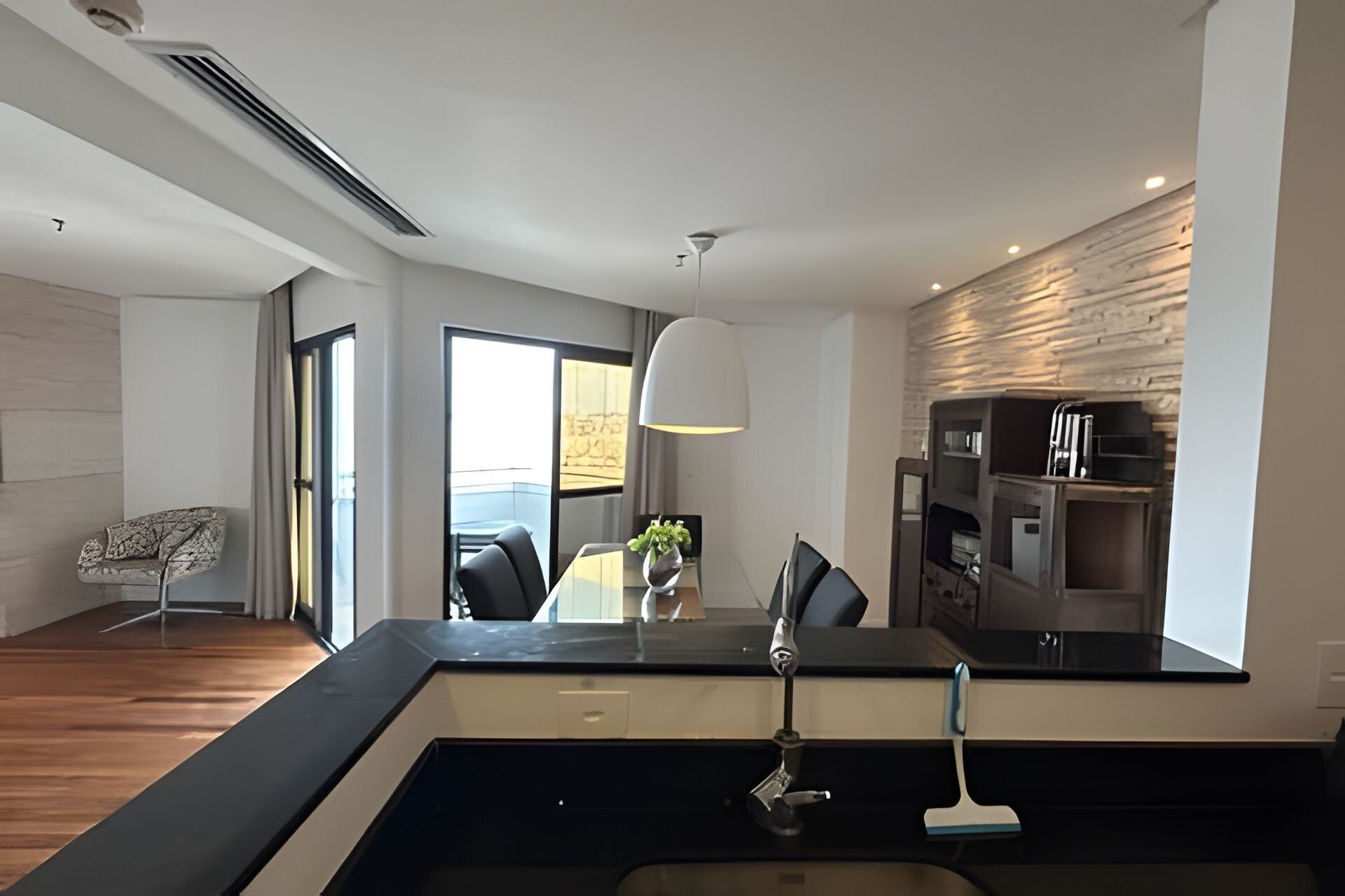 Una cocina moderna con encimera negra, un fregadero y una zona de comedor con una mesa y sillas.