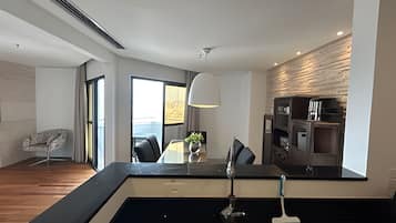 Una cocina moderna con encimera negra, un fregadero y una zona de comedor con una mesa y sillas.