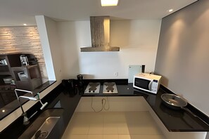 Una cocina moderna con encimera negra, electrodomésticos de acero inoxidable y un panel posterior de madera.