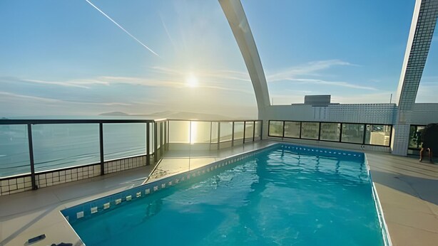 En modern inomhuspool med fri utsikt över havet och ett markant, böjt arkitektoniskt element.