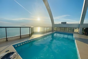 Una piscina interior moderna con vistas claras al mar y una característica arquitectónica curva distintiva.