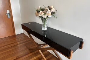 A modern room with a wooden floor, a black desk with a vase of flowers, and a door with a lock. - SHB Pôr do Sol Inesquecível  (Santos)