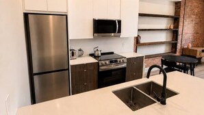 Una cocina moderna con electrodomésticos de acero inoxidable, gabinetes blancos y una pared decorativa de ladrillo.
