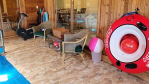 A wooden cabin interior with wicker furniture, a glass door leading outside, and a red inflatable ring. - Luxury Home with Indoor Pool, 3-bedroom house in delightful Milford MI (Milford)