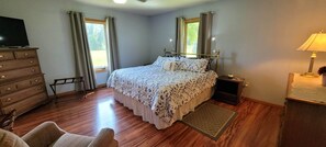 Ein Schlafzimmer mit Bett, Kommode, Nachttisch, Lampe und Fernseher.