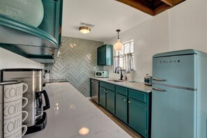 Eine Küche mit türkisblauen Schränken, einem Galanz-Kühlschrank, einer Kaffeemaschine und einer Mikrowelle.