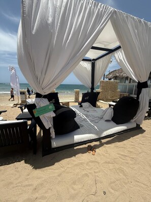 Eine Strandkabine mit Dach und Liege, mit Schild, dass sie reserviert ist.