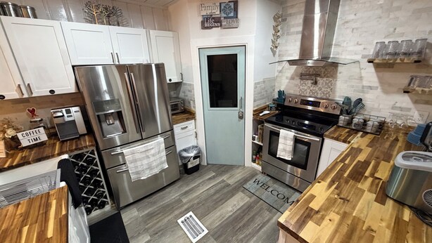 Una cocina moderna con electrodomésticos de acero inoxidable, una encimera de madera y un felpudo con la palabra 'Welcome'.
