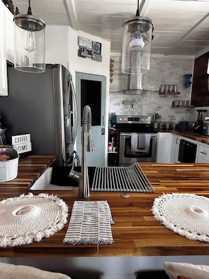 A modern kitchen with a stainless steel refrigerator, a coffee station, and a wooden dining table with placemats. - Romantic retreat/best fishing in central Fl. Close to springs and the villages (Lake Panasoffkee)