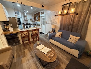 A cozy living room with a blue sofa, wooden coffee table, and a kitchen in the background. - Romantic retreat/best fishing in central Fl. Close to springs and the villages (Lake Panasoffkee)
