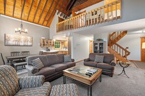 A spacious living area with a high ceiling, a dining table, sofas, and a staircase. - Stone Throw- Near Creek- Unique- Great Location (Hill City)