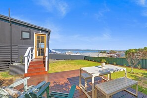 A residential property with a deck, outdoor seating, and a view of the sea.