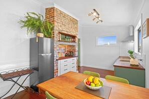 Una cocina moderna con pared de ladrillo, un refrigerador y un comedor con una mesa para dos.