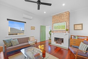 A living room with a fireplace, a sofa, a coffee table, and a television. - The Yellow Door on Spencer | Harbour Views (Albany)