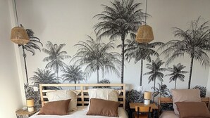 Ein Schlafzimmer mit einem großen Bett, einem Einzelbett, einem Schreibtisch und einem Stuhl. Auf dem Schreibtisch stehen zwei Lampen.