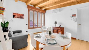 Un soggiorno moderno con un divano grigio, un tavolo da pranzo apparecchiato per quattro persone e un soffitto in legno.