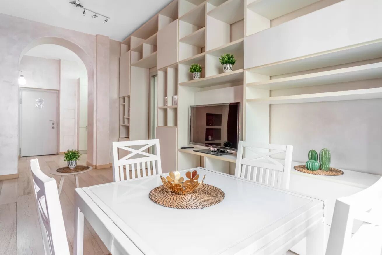 A modern dining area with a white table, chairs, and a decorative centerpiece.