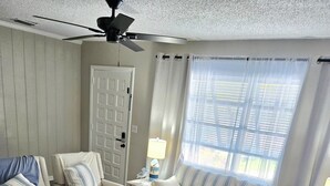 A living room with a sofa, armchairs, a coffee table, and a ceiling fan. - Stylish Pool Retreat in the Heart of Vero Beach. (Vero Beach)