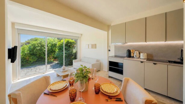 Una cocina moderna con zona de comedor, ventanas amplias y vistas al verdor.