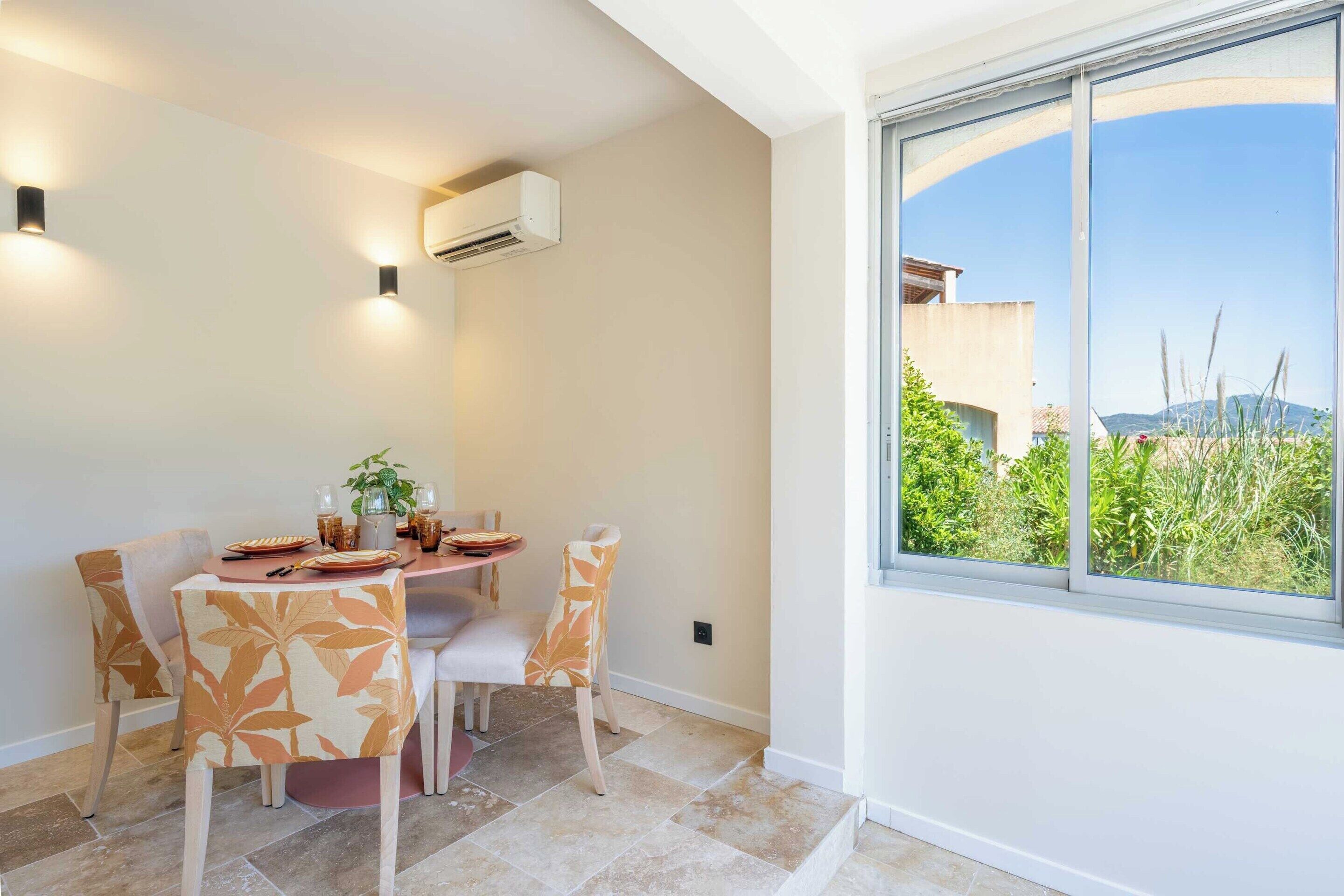 A dining area with a table, chairs, and an air conditioning unit.