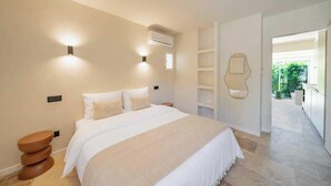 Un dormitorio con cama, mesitas de noche, aire acondicionado y vistas al exterior.