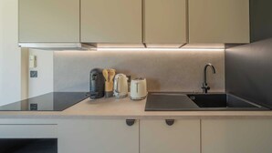 Una cocina moderna con cafetera expreso integrada, hervidor y tostadora.