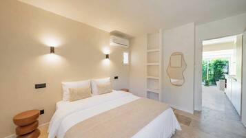 A modern bedroom with a large bed, bedside tables, and a built-in wardrobe.