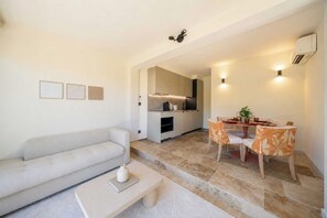 A modern living room with a sofa, coffee table, and dining area with chairs. - Modern House a/c Pool 1br/ 2P - Font Mourier (Cogolin)