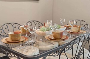 Una mesa de comedor dispuesta con platos, tazones, vasos y cubiertos.